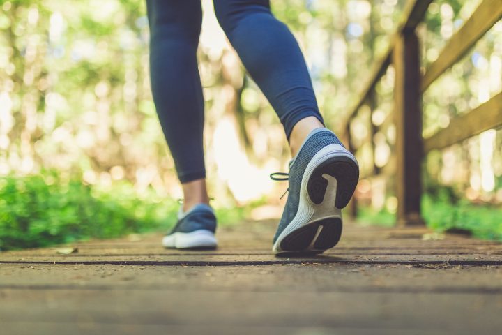 Close up of female legs with running shoes on wooden footpath in