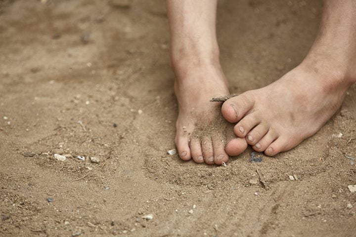 Dirty bare feet of poor little girl, selective focus, shallow depth of field.