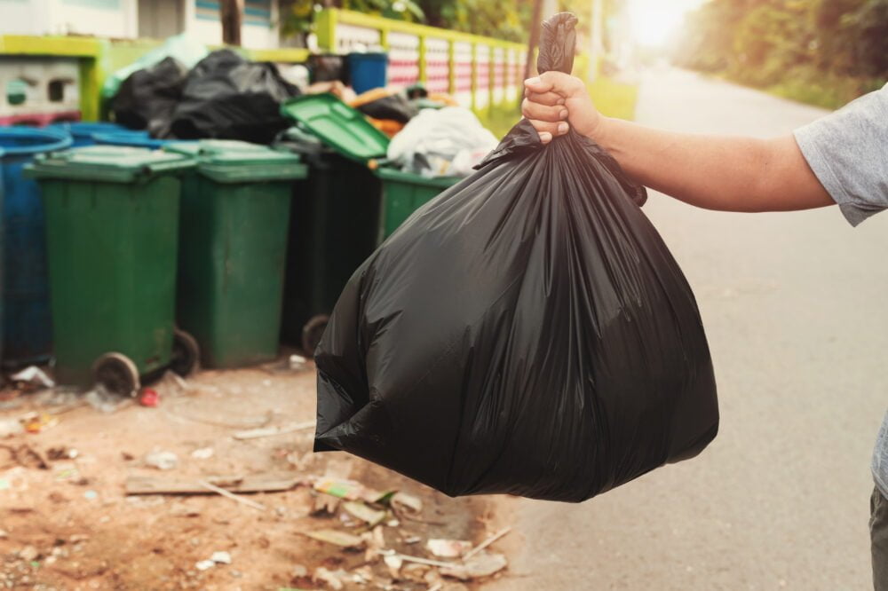 woman hand holding garbage in black bag for cleaning in to trash