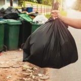 woman hand holding garbage in black bag for cleaning in to trash