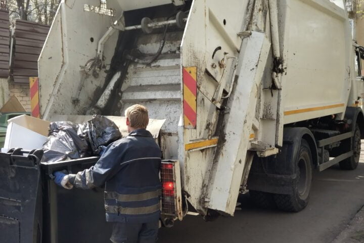 The cleaner loads a container with garbage and waste into the ga