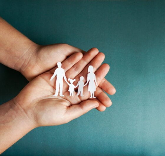 hands holding paper family cutout, social distancing concept, co