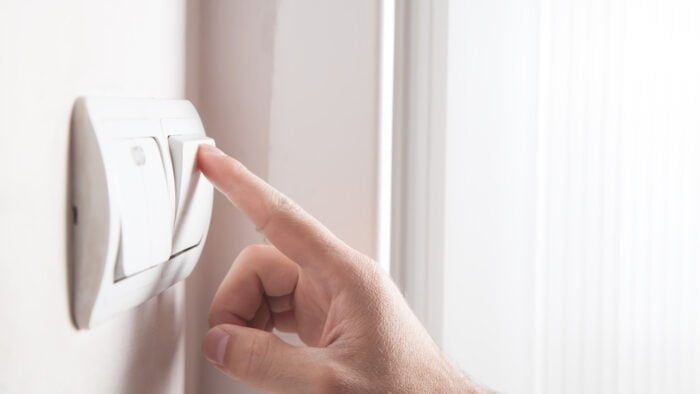 Hand turning off on light switch.