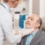 doctor in medical gloves checking patients throat in clinic