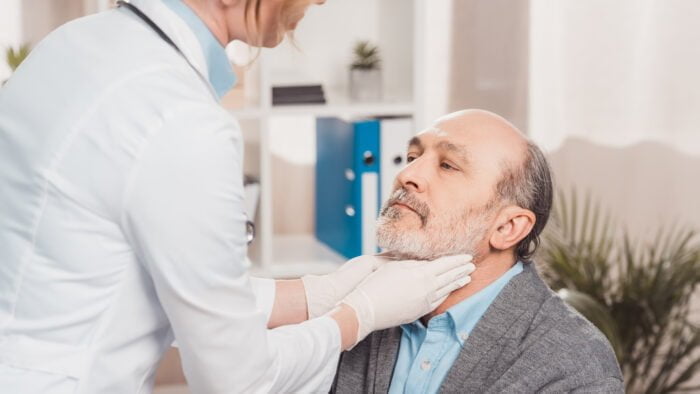 doctor in medical gloves checking patients throat in clinic