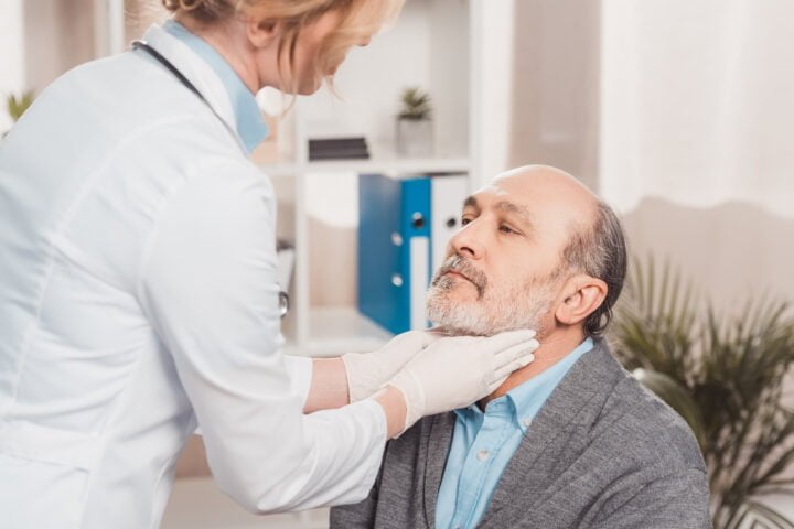 doctor in medical gloves checking patients throat in clinic