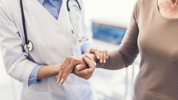 General practitioner is holding female hand in the hospital