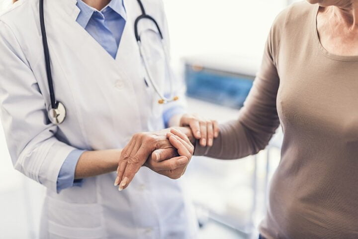 General practitioner is holding female hand in the hospital