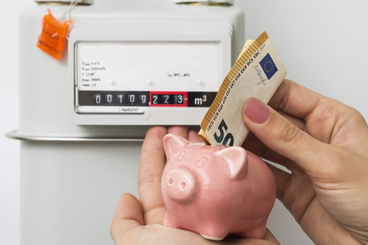 Energy saving concept. Woman's hand inserting Euro cash in piggy