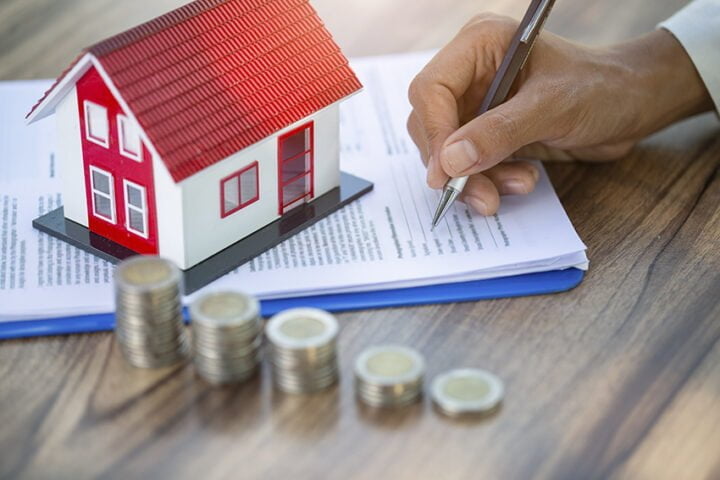 A woman signs a purchase agreement for a house in a real estate