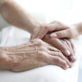 Young woman touching senior man hands, closeup
