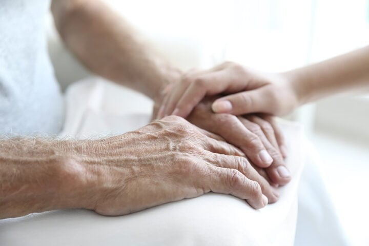 Young woman touching senior man hands, closeup