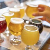 Female Hand Picking Up Glass of Micro Brew Beer From Variety on Tray