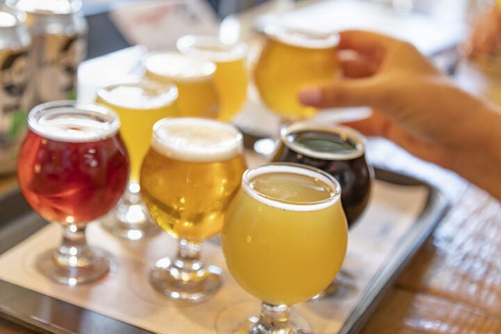 Female Hand Picking Up Glass of Micro Brew Beer From Variety on Tray