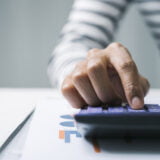 Close up business woman secretary using calculator to do math fi