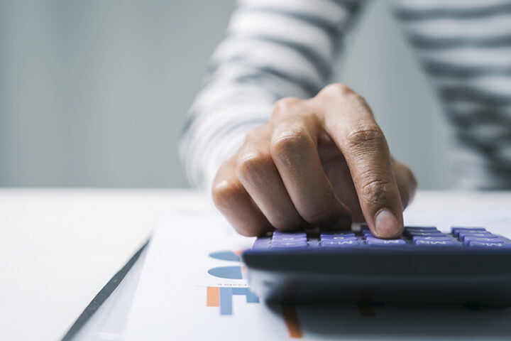 Close up business woman secretary using calculator to do math fi