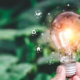 Hand holding light bulb ideas on a background of blurred green t
