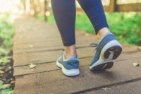 Woman runner feet walking in nature. Close up on shoes. Healthy