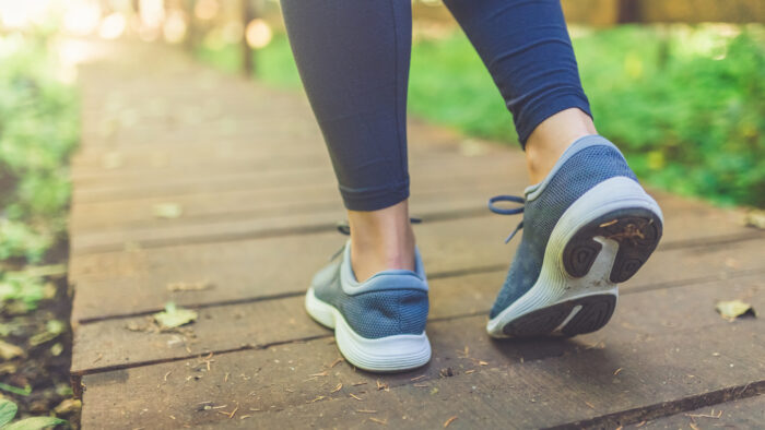 Woman runner feet walking in nature. Close up on shoes. Healthy