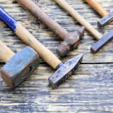 Old iron hammers lie on a wooden table.