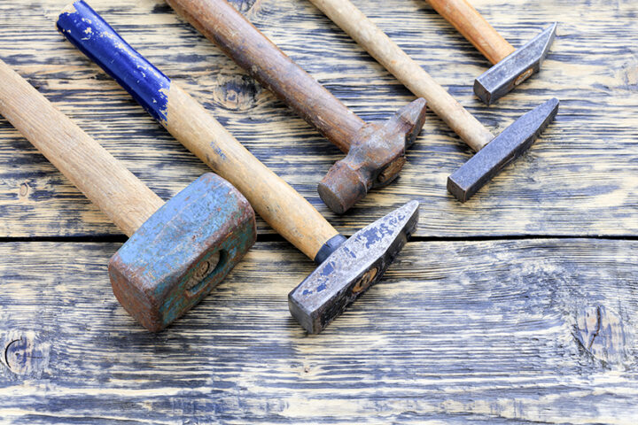 Old iron hammers lie on a wooden table.