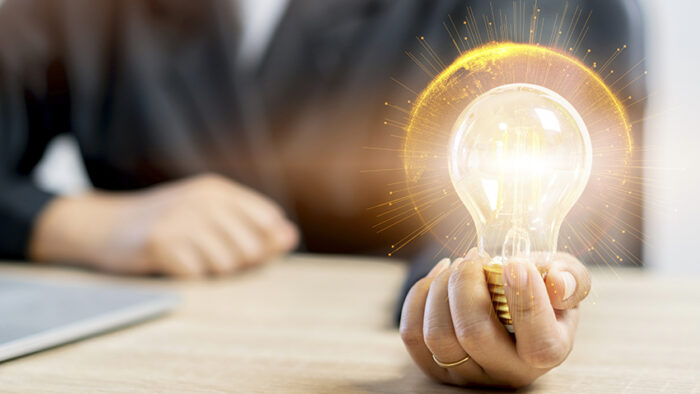 Hand of businesswoman holding illuminated light bulb cover with