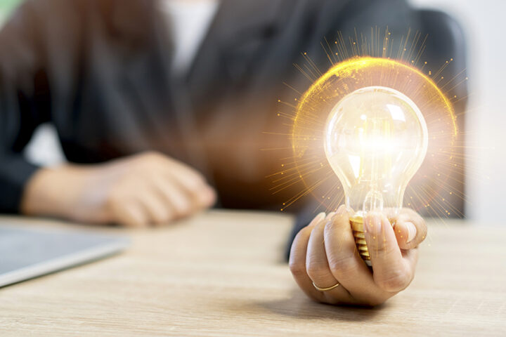 Hand of businesswoman holding illuminated light bulb cover with