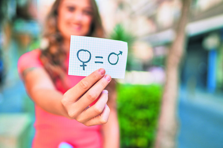 Young blonde girl smiling happy holding paper with gender equality concept walking at the city.