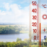 The thermometer on a background of summer landscape in sunny weather shows 25 degrees heat_