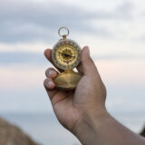 Compass in the hand on the nature background
