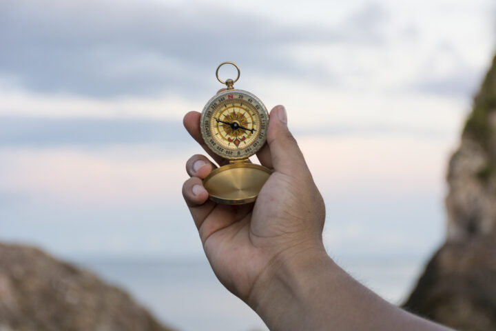 Compass in the hand on the nature background