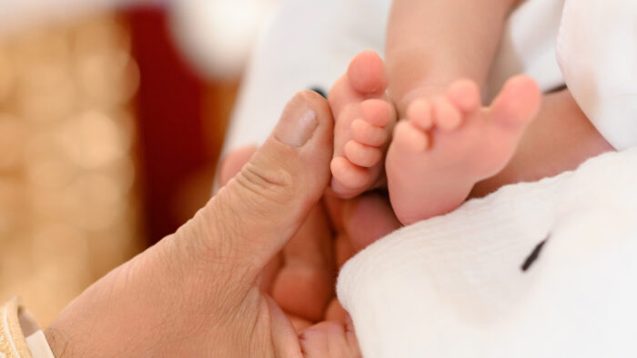 The priest performs the rite of baptism of the child and anoints the leg with holy peace.