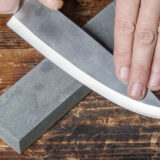 Knife sharpening. Hands holding knife and whetstone on  the old