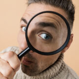 Close up of a man looking into a magnifying glass