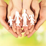 Paper family in hands on bright background