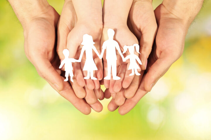 Paper family in hands on bright background