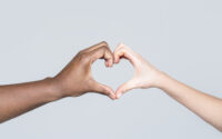 People different skin colors put their hands together making heart shape in white background. Charity, love and diversity - closeup of female and male hands of different skin color making