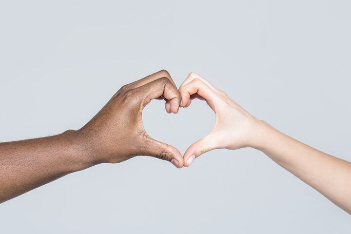 People different skin colors put their hands together making heart shape in white background. Charity, love and diversity - closeup of female and male hands of different skin color making