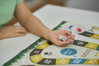 Closeup of unrecognizable young woman playing board game with friends