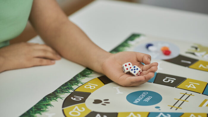 Closeup of unrecognizable young woman playing board game with friends