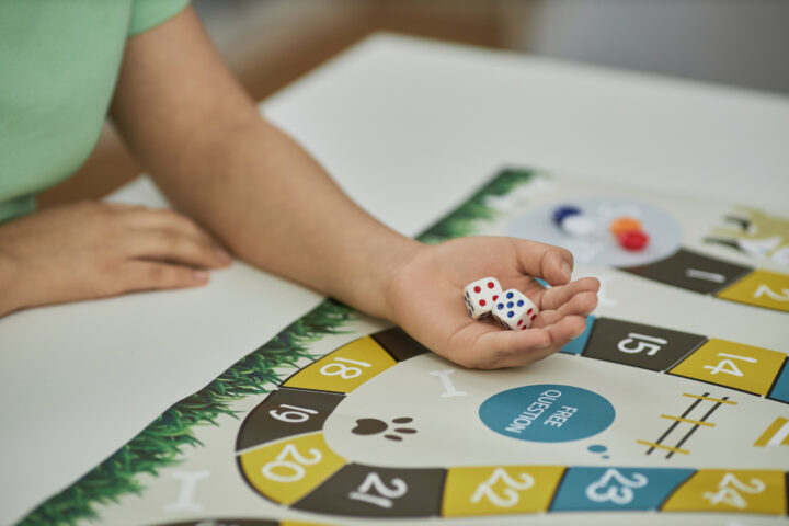Closeup of unrecognizable young woman playing board game with friends