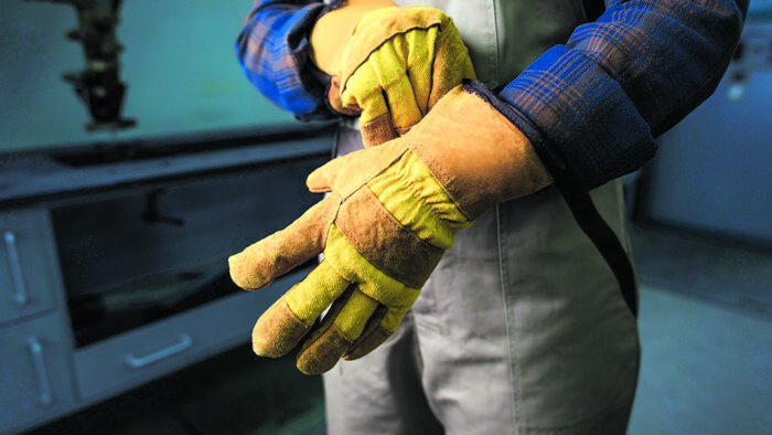 Cropped view of welder wearing gloves in factory