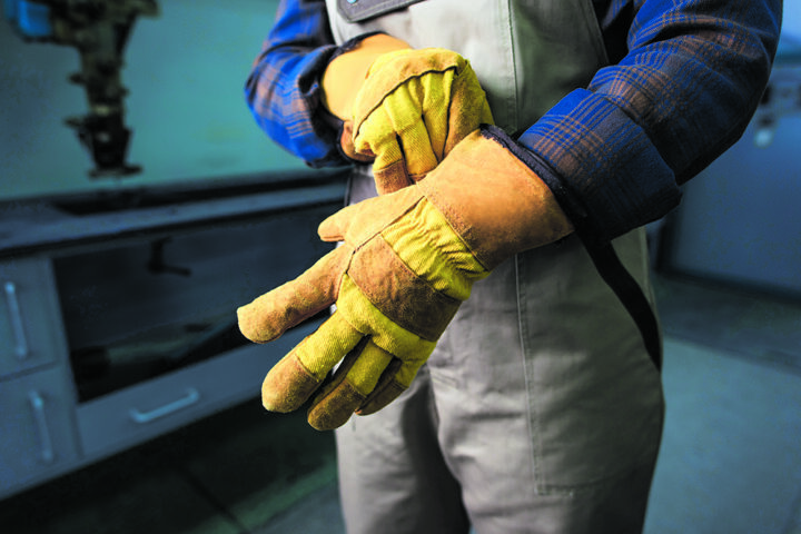 Cropped view of welder wearing gloves in factory