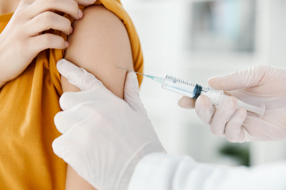 doctor injects a vaccine into the shoulder of a female patient in a medical mask in a hospital side view