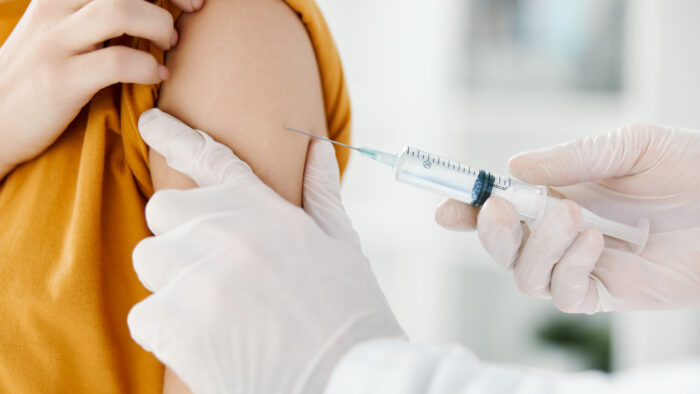 doctor injects a vaccine into the shoulder of a female patient in a medical mask in a hospital side view