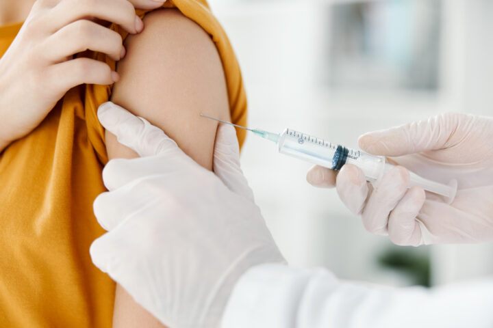 doctor injects a vaccine into the shoulder of a female patient in a medical mask in a hospital side view